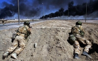 Two British soldiers take up position on the road to Basra as burning oil fills the sky April ,2003