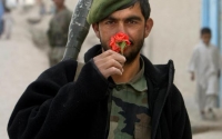 A member of the Afghan National Army pauses to smell a flower
