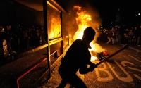 A demonstrator strikes a bus shelter